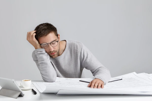 Tired young attractive man sleeps work place has much work being fatigue exhausted