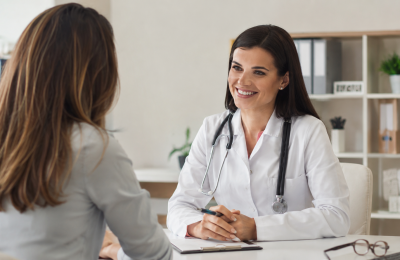 Médica realizando consulta preventiva com paciente em consultório moderno e acolhedor, destacando a importância do acompanhamento médico regular para prevenção de doenças e promoção da saúde.