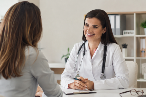 Médica realizando consulta preventiva com paciente em consultório moderno e acolhedor, destacando a importância do acompanhamento médico regular para prevenção de doenças e promoção da saúde.